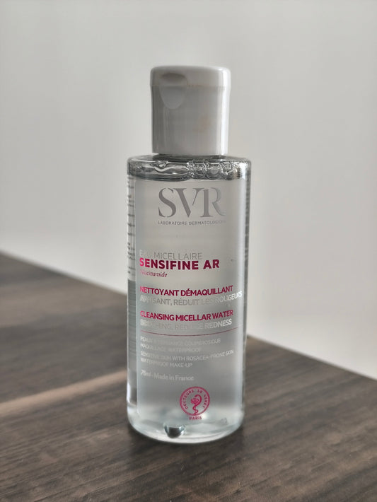 Bottle of SVR Sensifine AR cleansing micellar water on a wooden surface with a white background